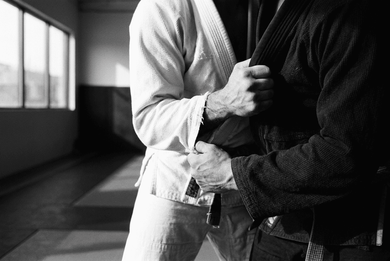 Close-up editorial visual of two jiu-jitsu athletes gripping their training gis